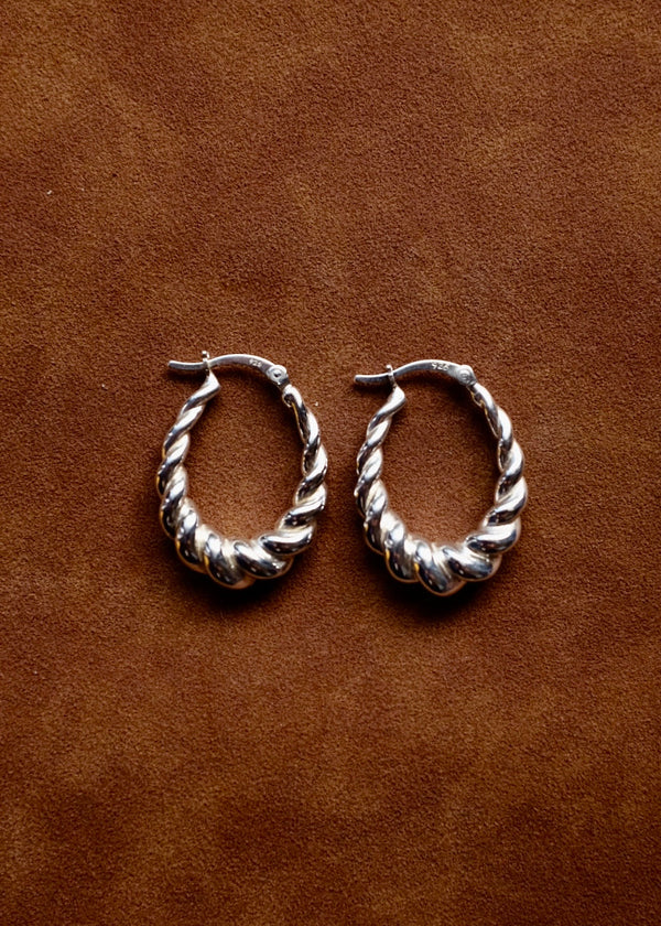 Pair of silver hoop earrings on a brown leather background