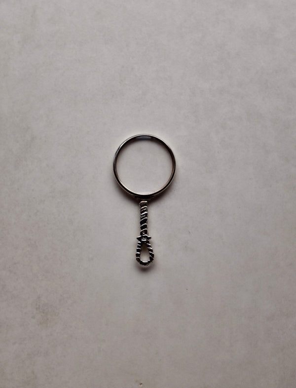 Small magnifying glass charm on a light gray background
