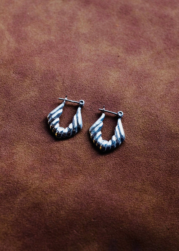 Silver hoop earrings on a brown leather surface