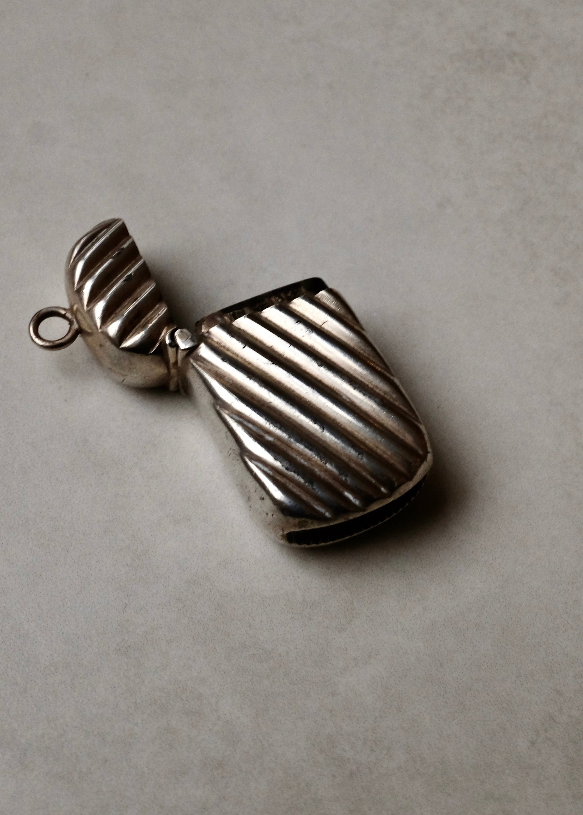 Silver pendant with ribbed texture on a gray background