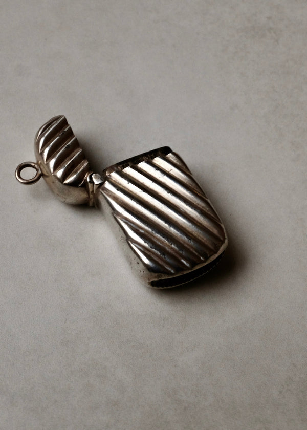 Silver pendant with ribbed texture on a gray background