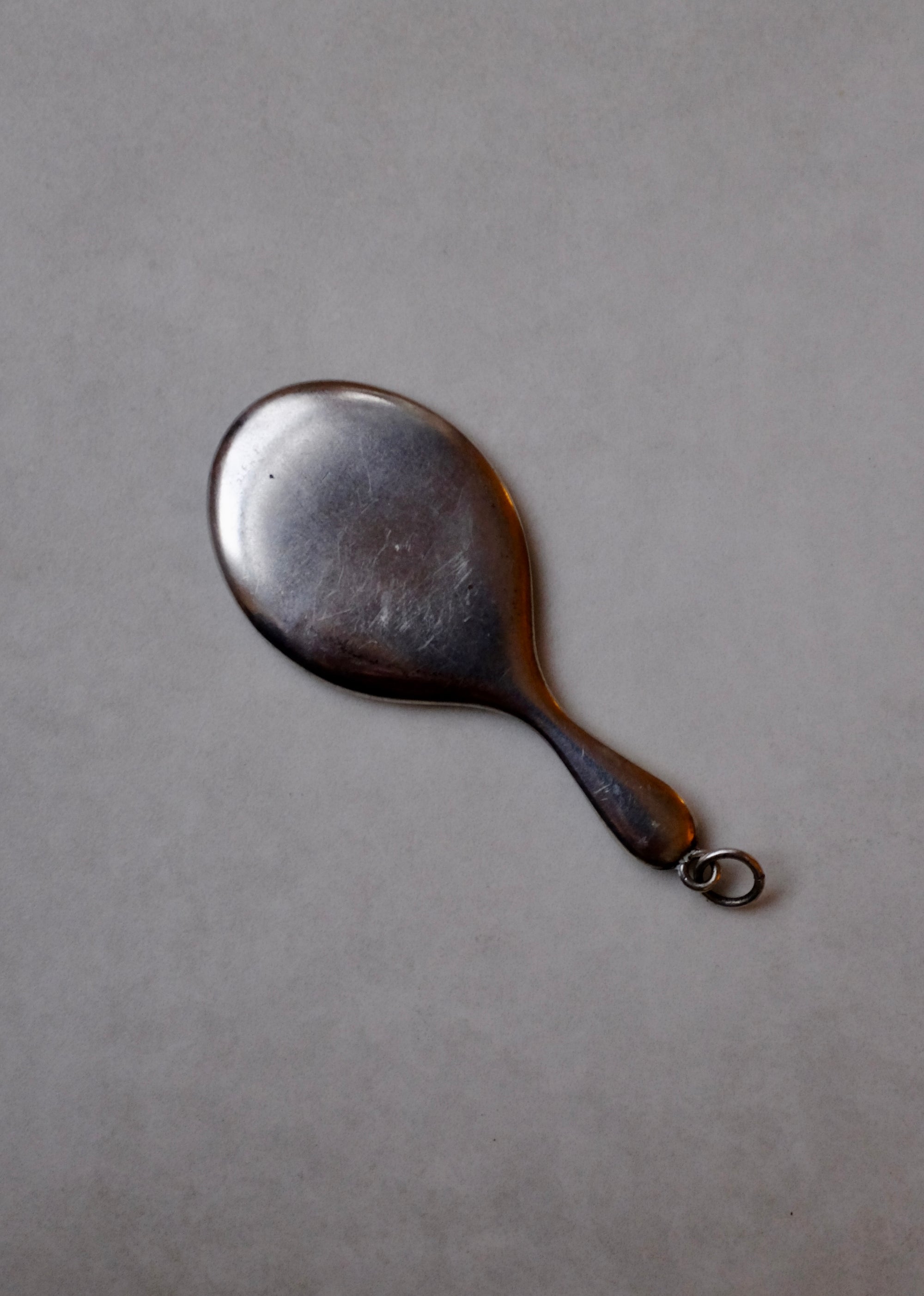 Small metal hand mirror on a gray background
