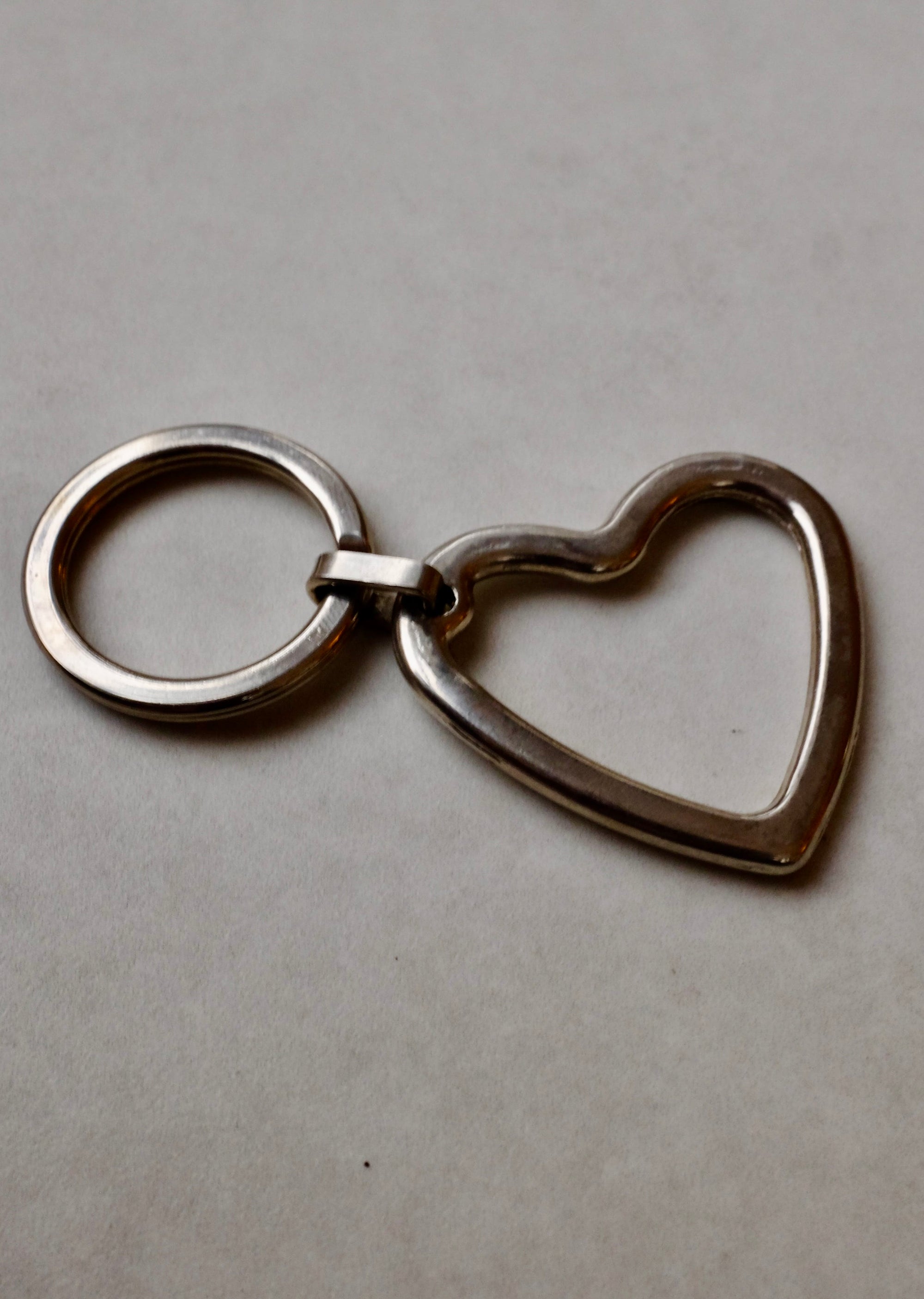 Silver heart-shaped keychain on a gray background