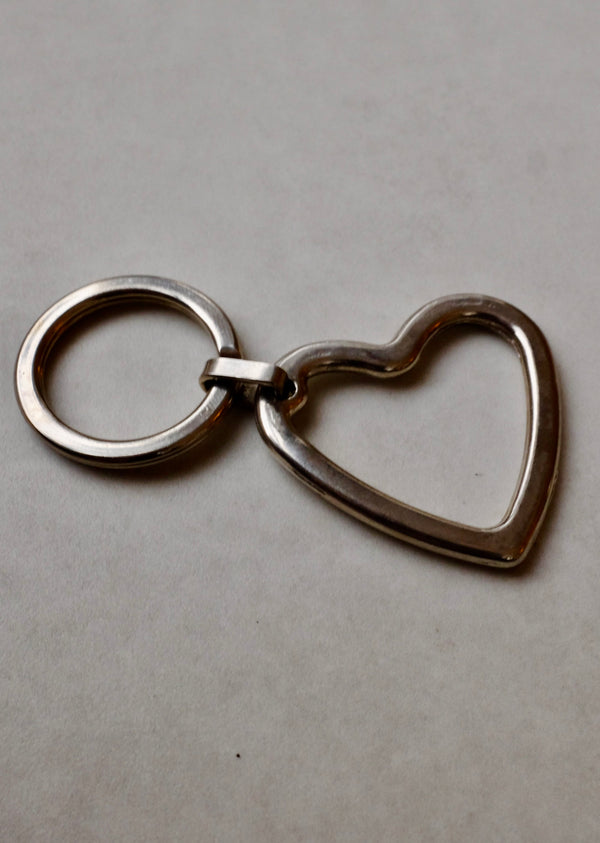 Silver heart-shaped keychain on a gray background