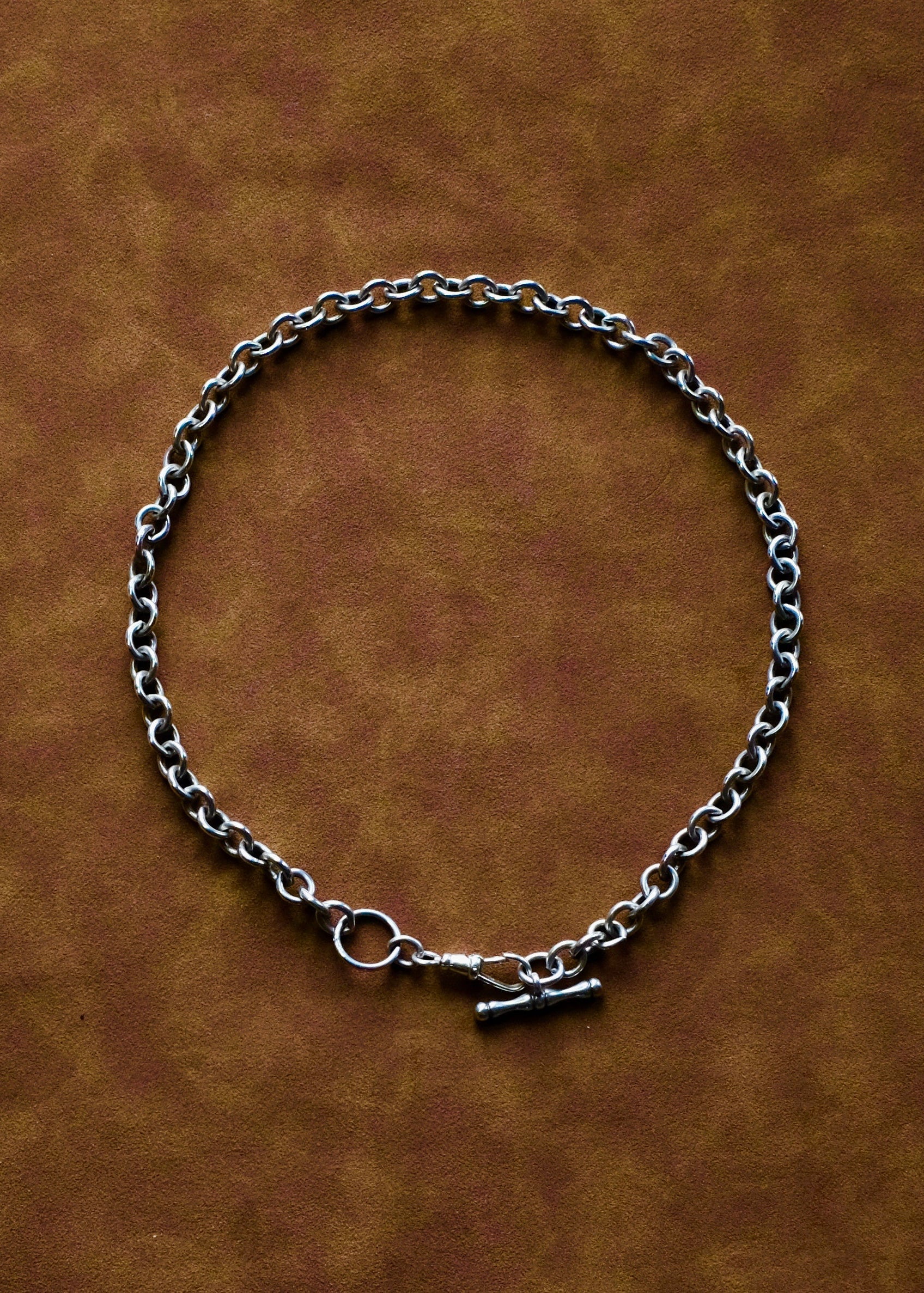 Silver chain necklace on a brown leather background
