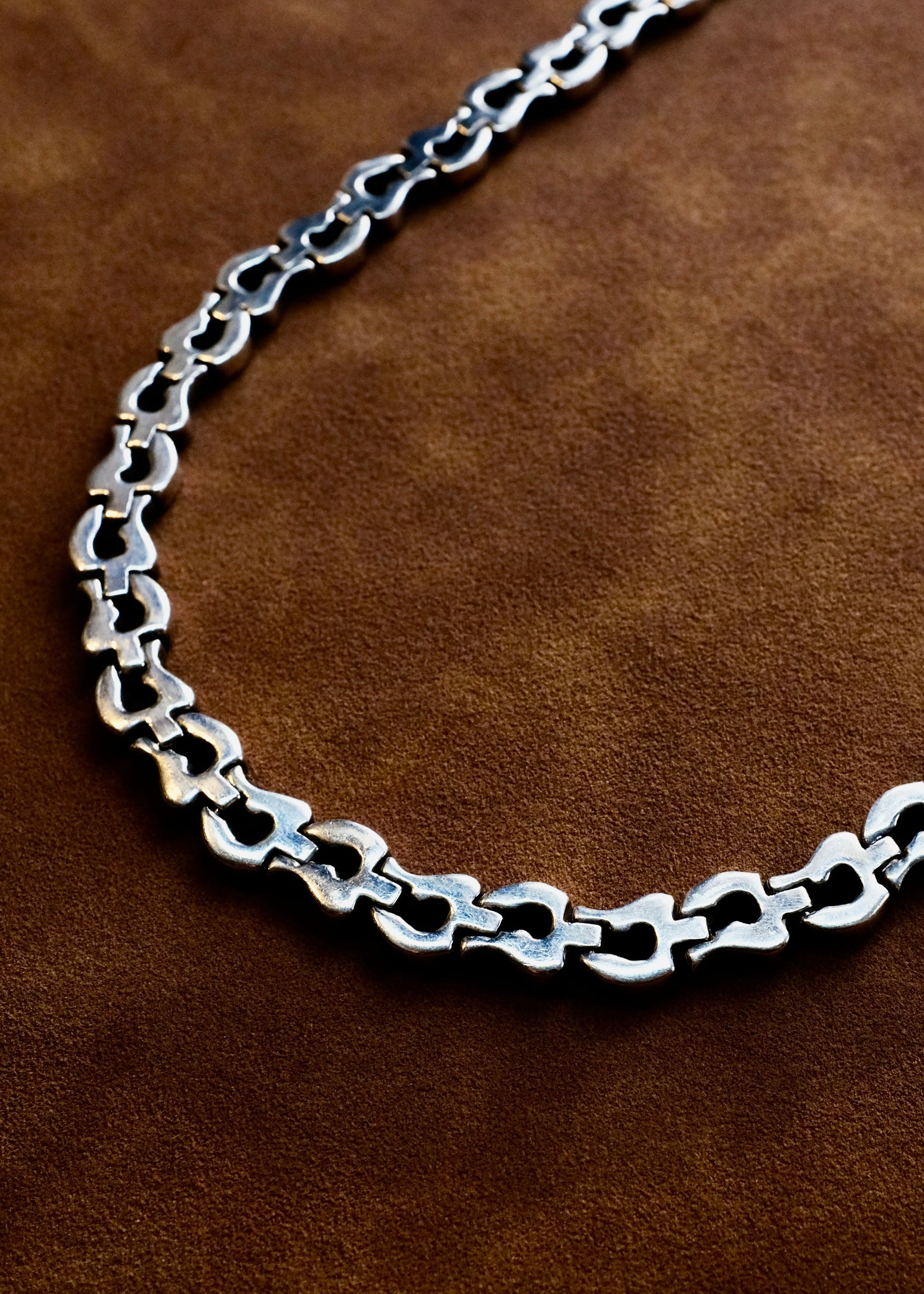 Silver chain necklace on a brown leather background