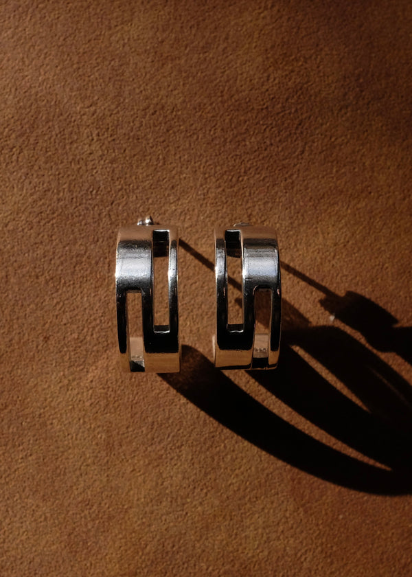 Silver hoop earrings on a brown textured surface