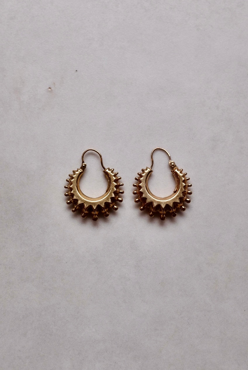 Pair of gold hoop earrings on a light gray background
