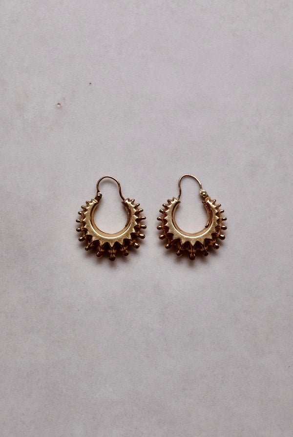 Pair of gold hoop earrings on a light gray background