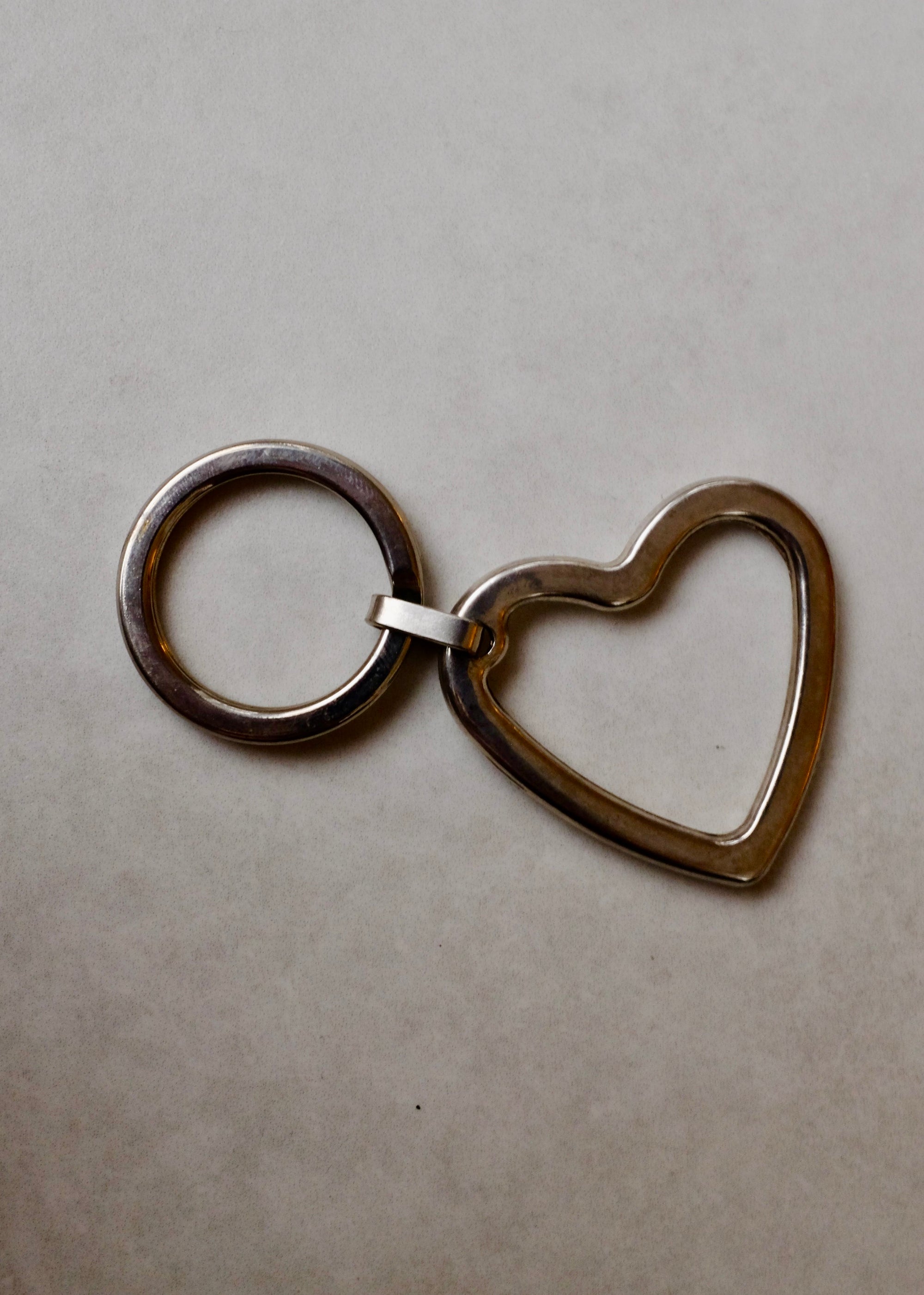 Metal keychain with heart and circular design on a beige background