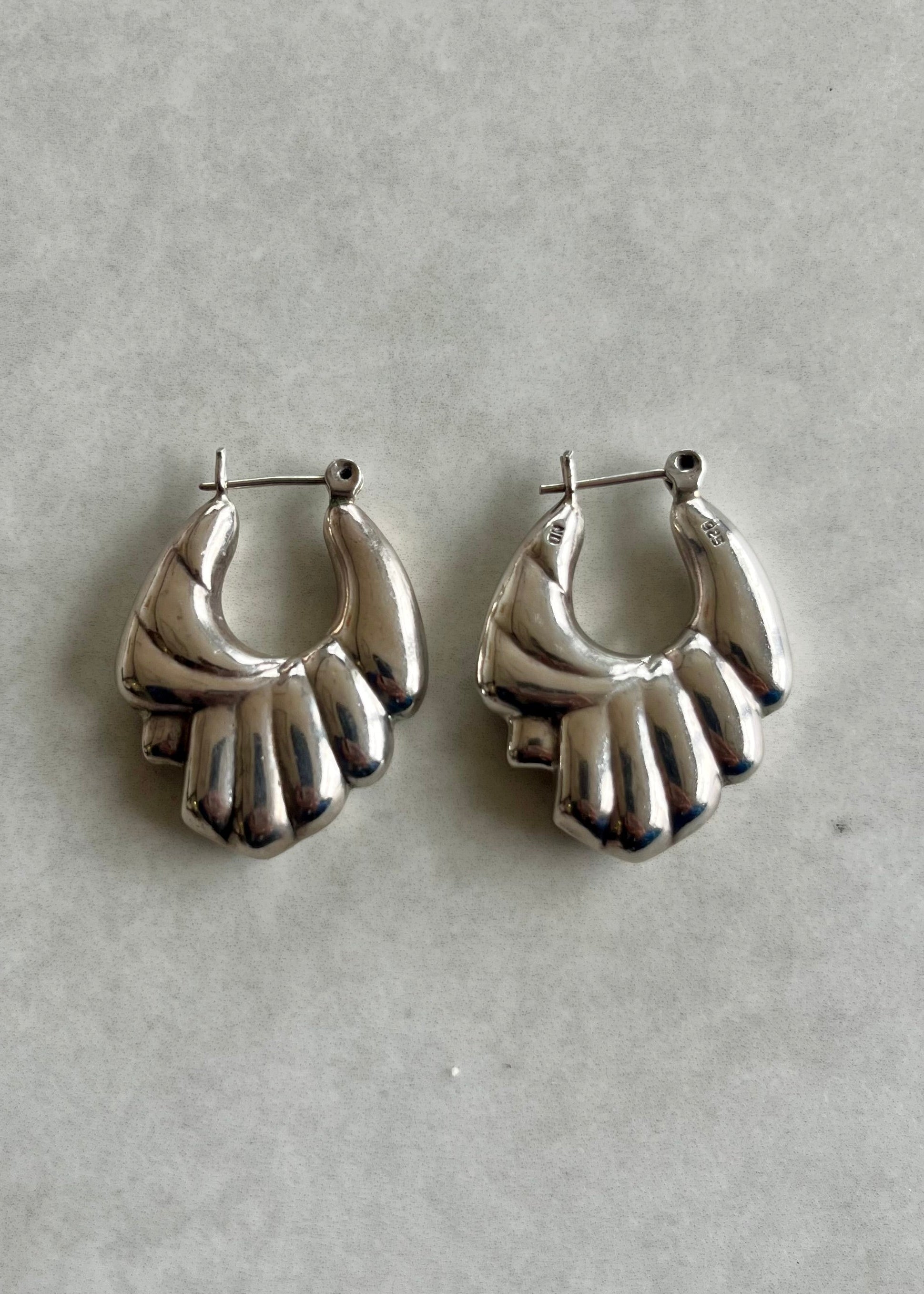 Pair of silver hand-shaped earrings on a light gray background