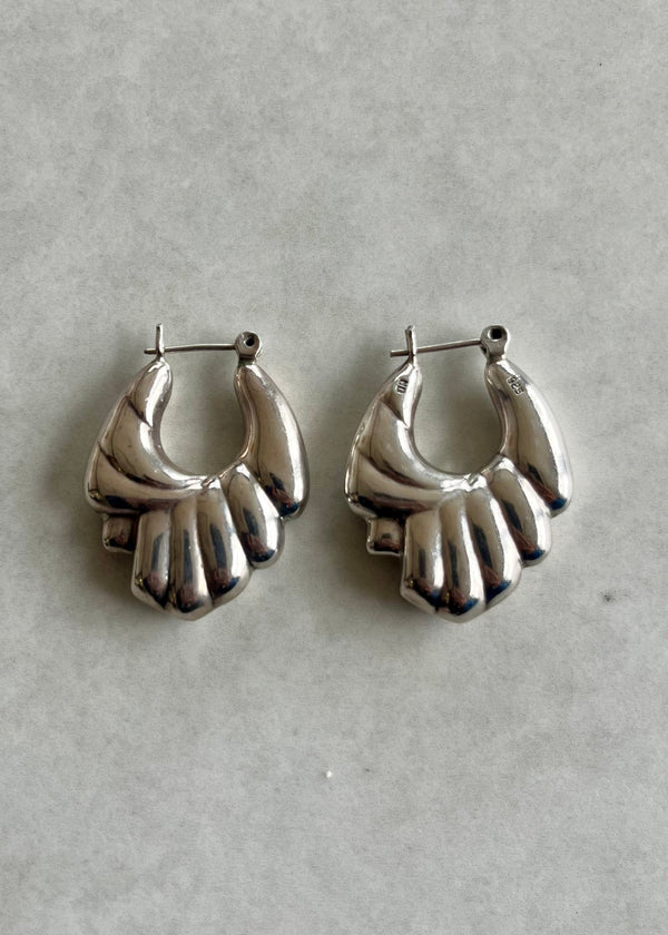 Pair of silver hand-shaped earrings on a light gray background