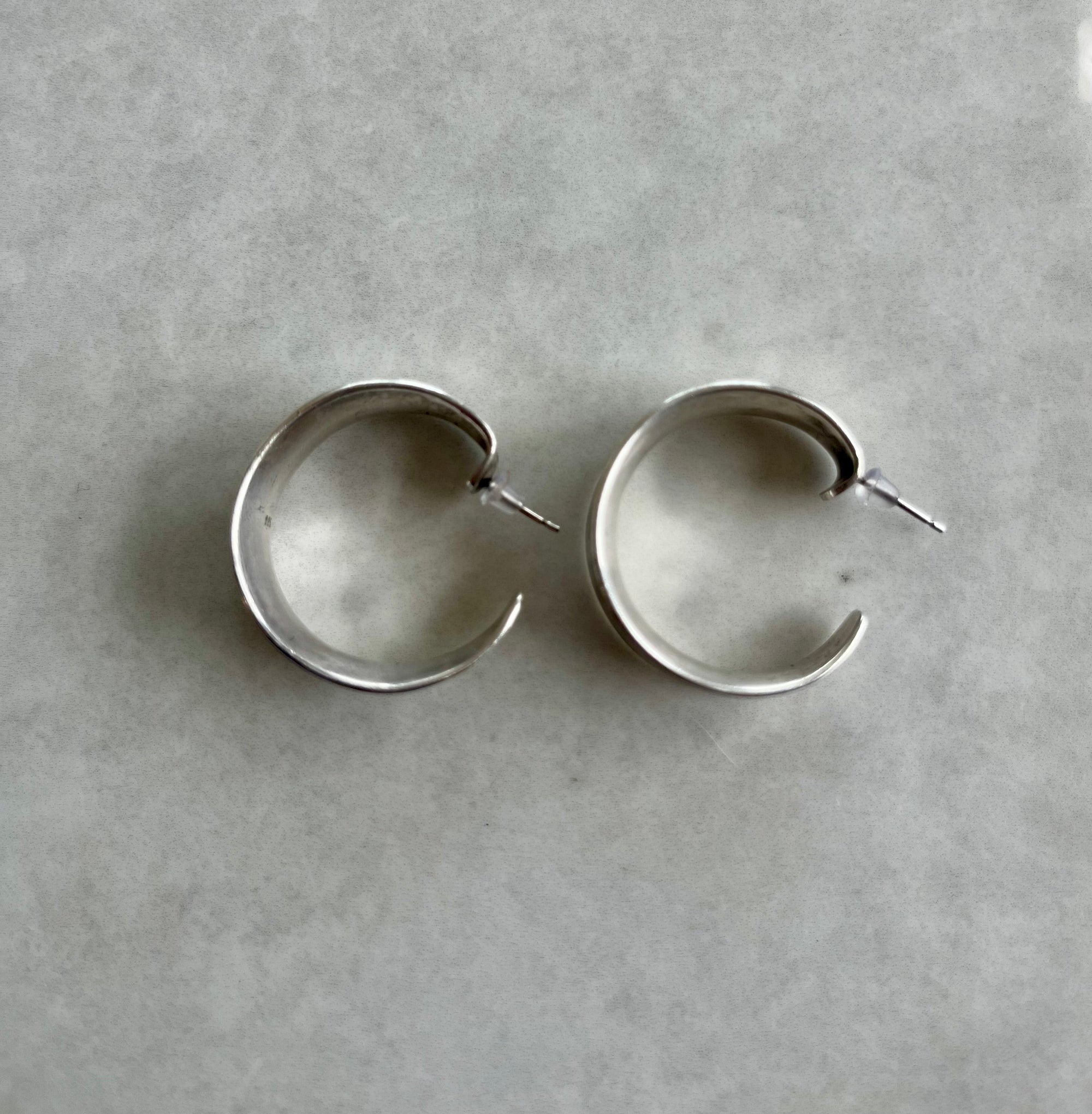 Pair of silver hoop earrings on a gray background