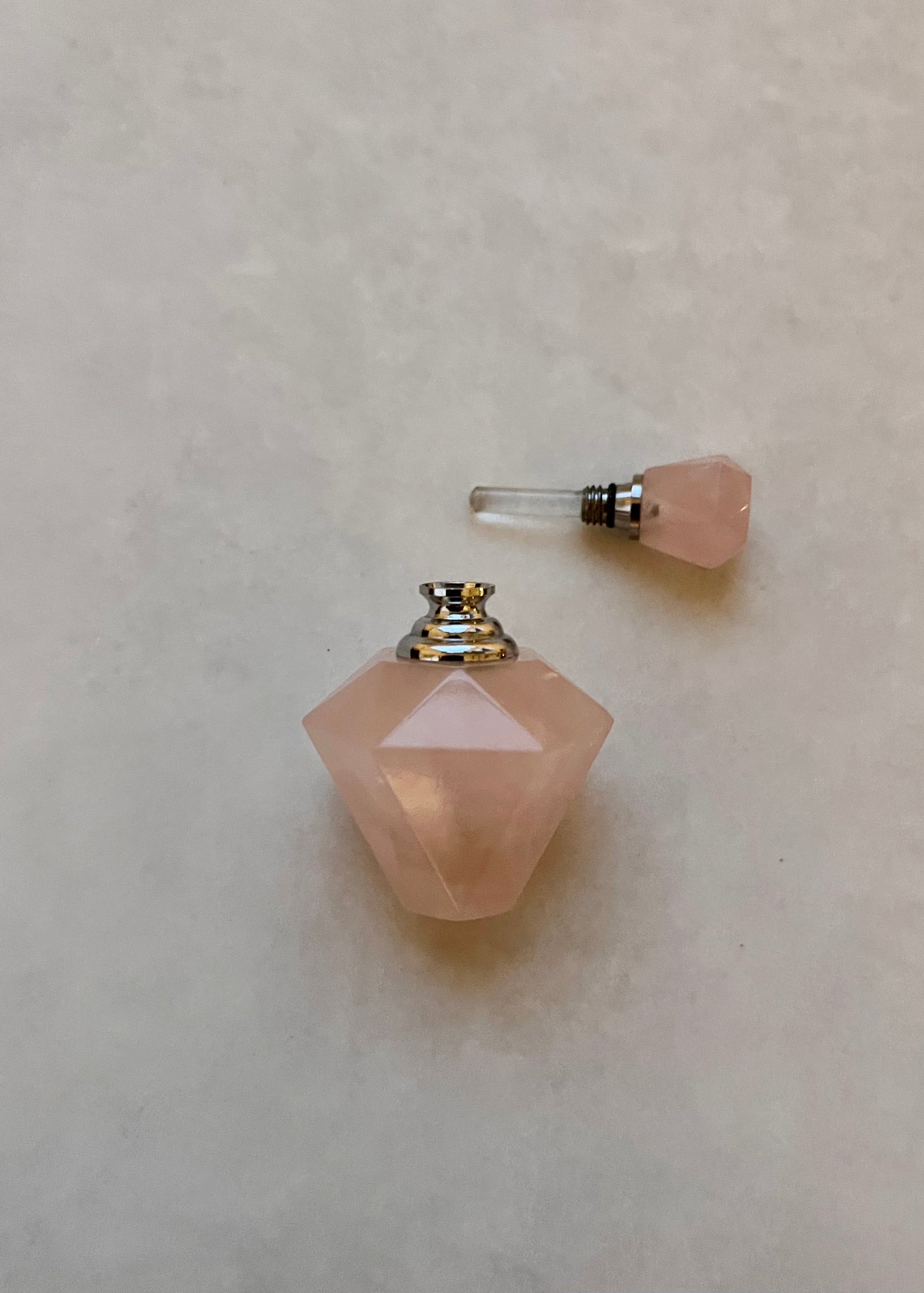 Pink gemstone-shaped perfume bottle on a light gray background