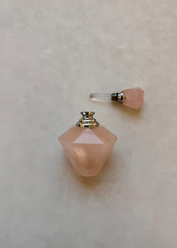 Pink gemstone-shaped perfume bottle on a light gray background