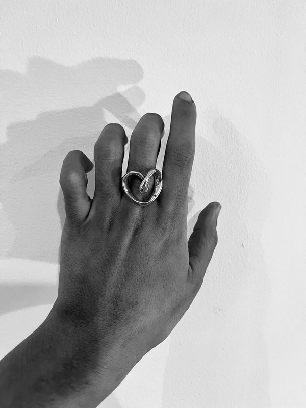 Hand wearing a silver ring with a stone on a light background