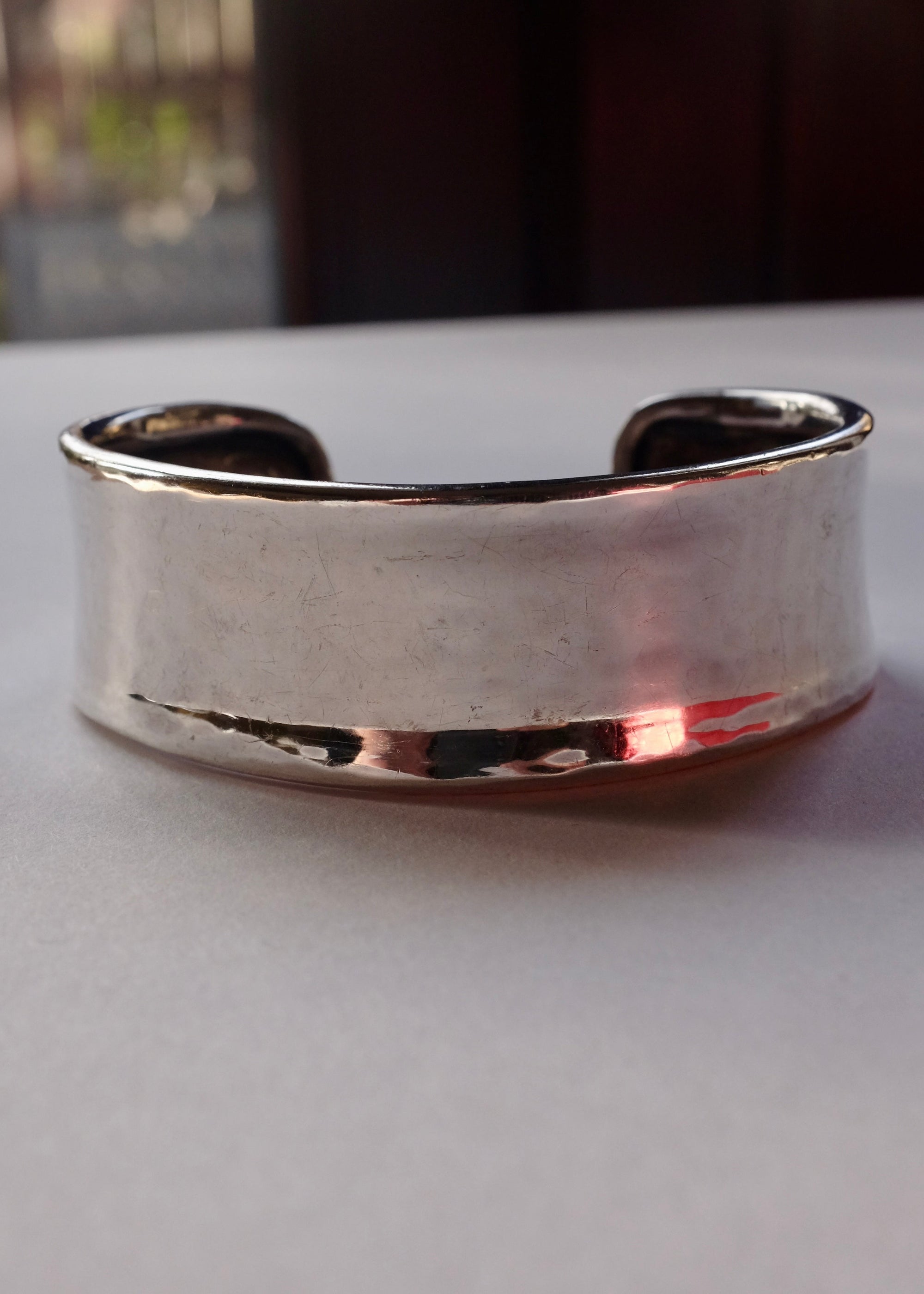 Silver bracelet on a light surface with a blurred background