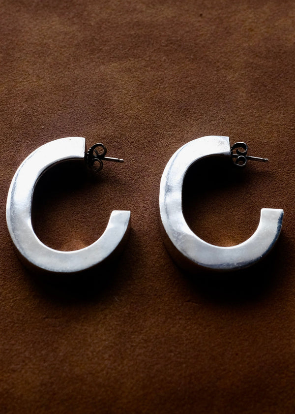 Pair of silver hoop earrings on a brown background